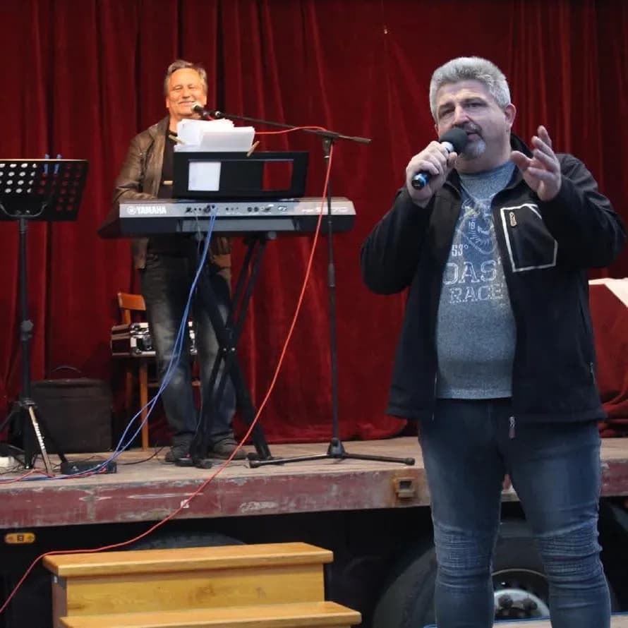 Jiří Šarman s mikrofonem na pódiu s kapelou